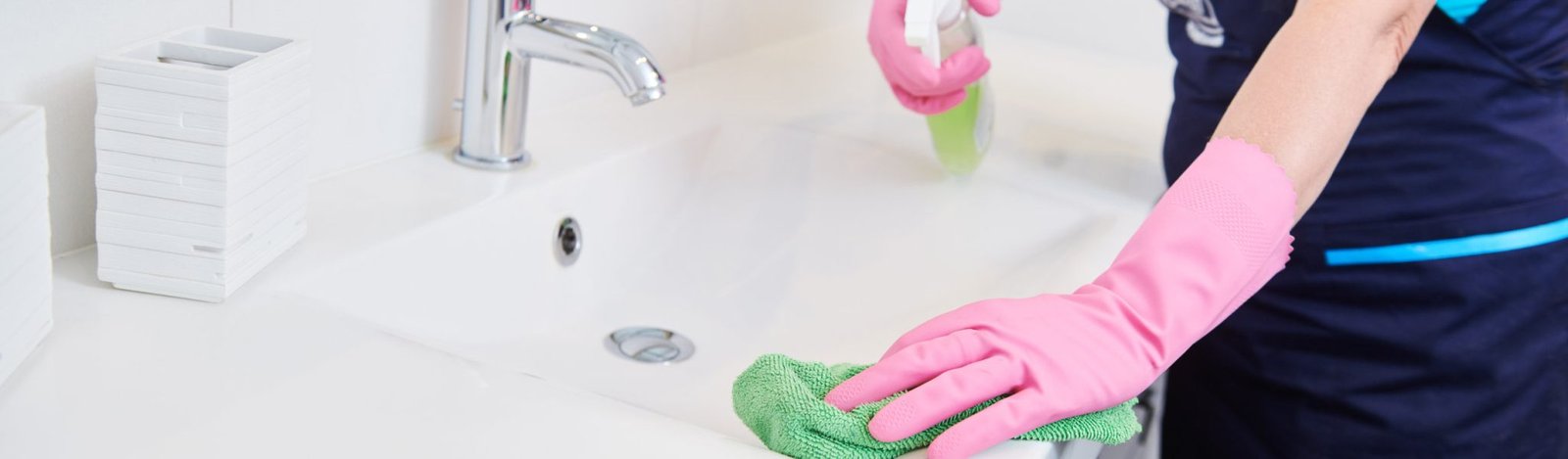 cleaning service. wiping bathroom washbasin surface with cloth and liquid cleaner